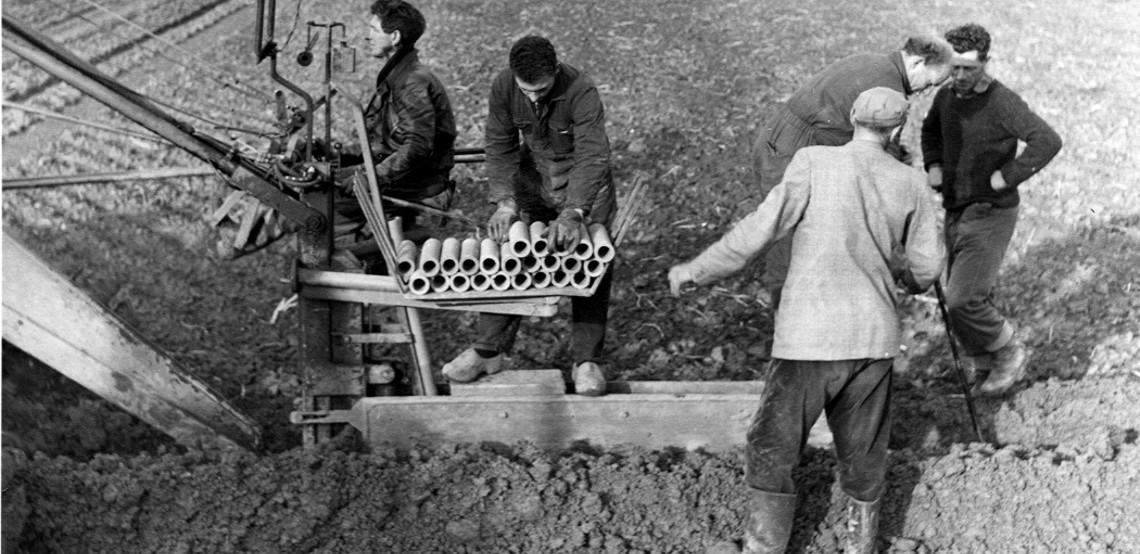 Black and white photo of 5 people using a historical Mastenbroek drainage trencher 