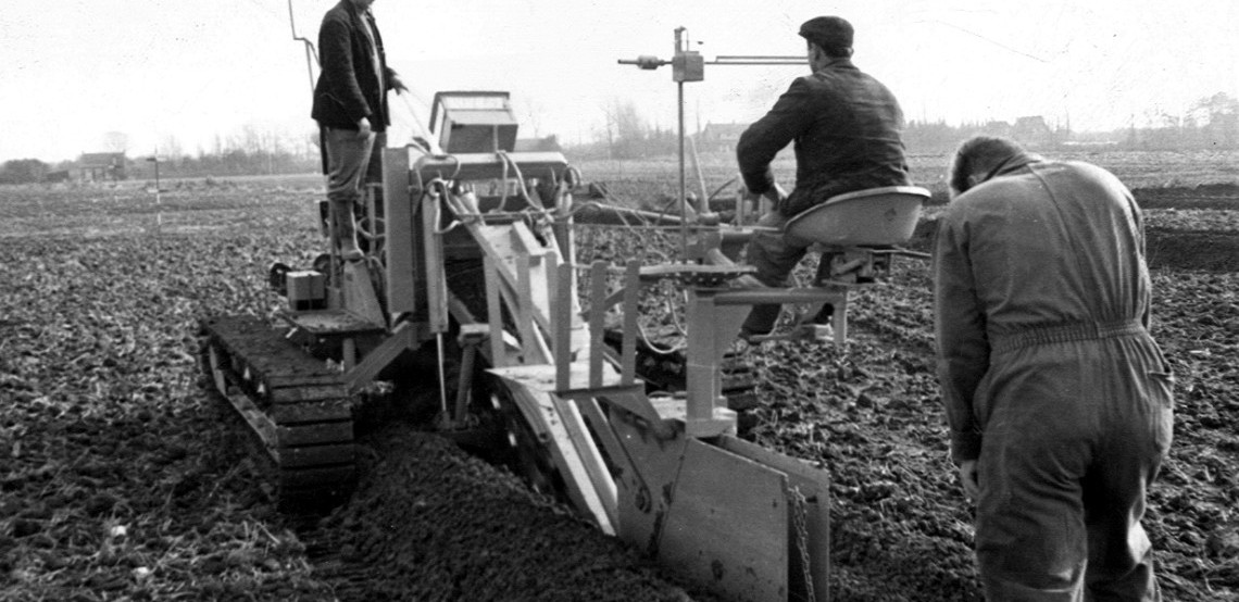 Black and white photo of an early Mastenbroek team working on agricultural drainage equipment