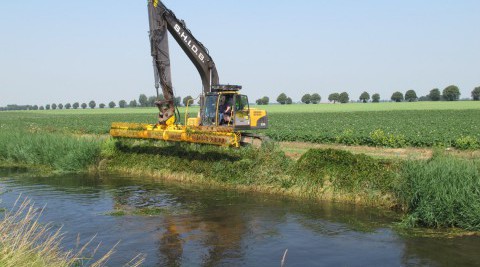 A Herder mowing bucket cutting back vegetation along a water course